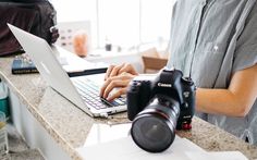 a man sitting in front of a laptop computer on top of a counter next to a camera