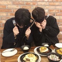 two people sitting at a table with plates of food and forks in front of them