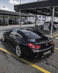 a black sports car parked in front of a gas station