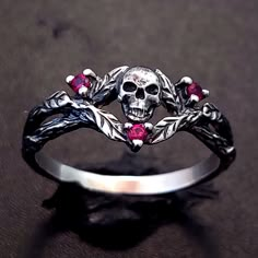 a skull and crossbone ring with red stones in the center on a black surface