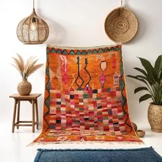 an orange and blue rug sitting on top of a wooden floor next to two planters