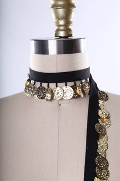 a mannequin wearing a black and gold choker with coins on the neck