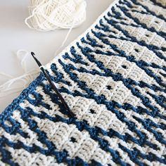 a crocheted blanket with yarn and knitting needles