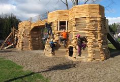 children are climbing up and down the wooden play structure made out of pallet boards