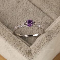 a white gold ring with an amethyst purple stone in it's center