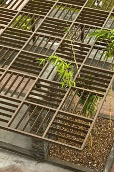 a metal structure sitting on top of a sidewalk next to a lush green planter