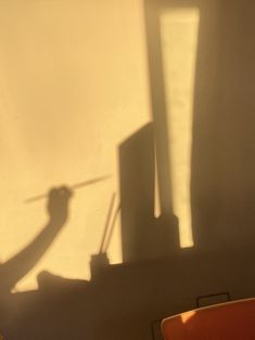 the shadow of a person standing in front of a wall with a knife on it