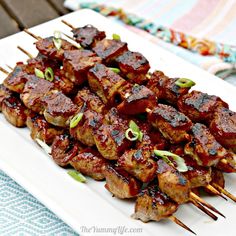 the skewers are covered with meat and vegetables on a white plate, ready to be eaten