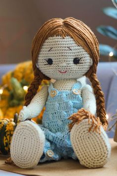 a crocheted doll sitting on top of a table next to some pumpkins