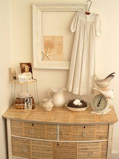 an old dresser with music sheets and other items on it in front of a framed photograph