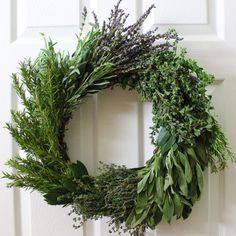 a wreath is hung on the front door with greenery and lavender sprigs