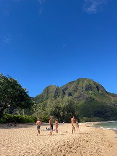 some people are walking on the beach and there is a mountain in the background