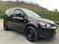 a black van parked on the side of a road next to a lush green hillside