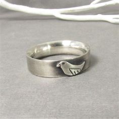 Chirp...sweet little sterling silver bird ring crafted from thick silver stock. A nice weight to this unisex ring and super comfortable due to the comfort fit styled band. The little bird has detailing to make it stand out and the ring has a soft brushed finish and oxidized to emphasize the details. The band measures a little over 5mm wide and almost 2mm thick. A sturdy ring to last the test of time and a perfect gift for your favorite bird watcher or nature lover. Artisan metalsmith jewelry by Unique Silver Jewelry With Bird Design, Bird Ring Jewelry, Silver Sterling Silver Necklace With Bird Design, Silver Bird Ring, Sterling Silver Bird Pendant Jewelry, Metalsmith Jewelry, Bird Ring, Bird Rings, Silver Bird