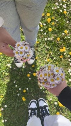 two people holding hands with daisies in the middle of their legs, and one person's shoes on