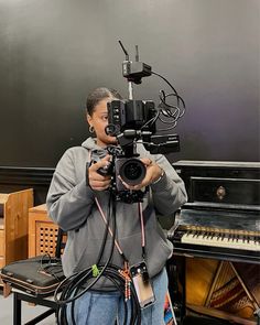 a man holding a video camera in front of a piano and other musical instrument equipment