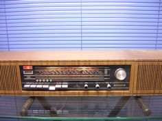 an old fashioned radio sitting on top of a glass shelf in front of a blue wall