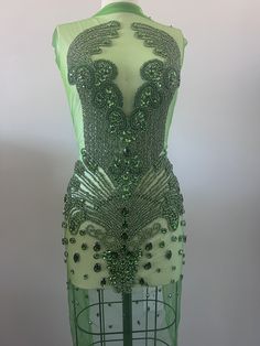 a green dress with sequins on it is sitting on a mannequin