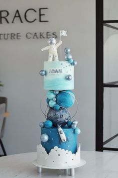 a three tiered cake with blue and white decorations on the top is displayed in front of a sign that reads grace future cakes