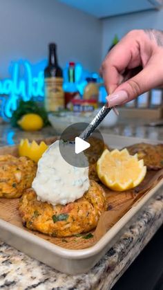 a person cutting up food on top of a wooden tray with lemon wedges and mayonnaise