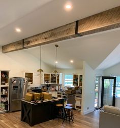 an open concept kitchen and living room with wood flooring, white walls and exposed beams