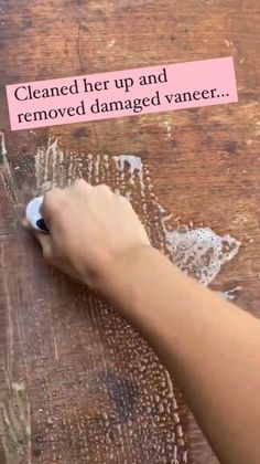 a person using a marker to remove damaged varer from a wooden table with text on it