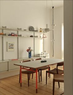 a dining room table with chairs and shelves on the wall