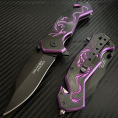 two knifes sitting on top of a black table next to each other with purple designs