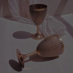 two wine goblets sitting next to each other on a white tableclothed surface