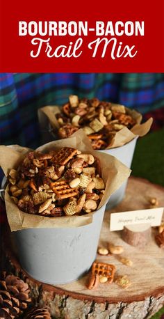 two buckets filled with trail mix sitting on top of a wooden table next to pine cones