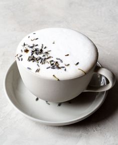 a white cup filled with lots of lavender sprinkles on top of a saucer