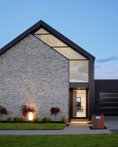 a modern house with an entry way leading to the front door and grass lawn area