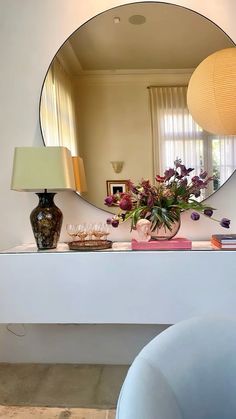 a mirror sitting on top of a white table next to a vase with flowers in it