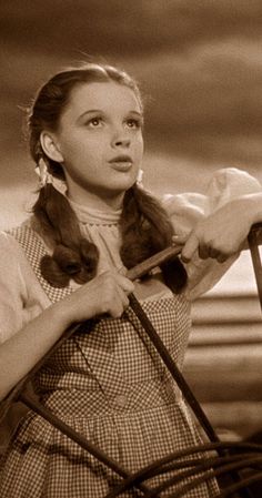 an old photo of a woman holding a horse's bridle and looking at the camera