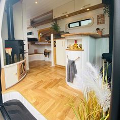 the interior of a camper with wood floors and white cabinets, including an oven