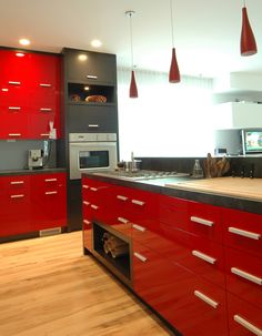 a modern kitchen with red cabinets and stainless steel appliances