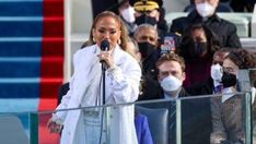 a woman wearing a face mask and holding a microphone in front of a group of people