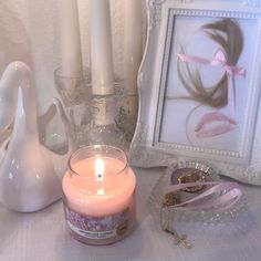 a pink candle sitting on top of a table next to a framed photo and other items