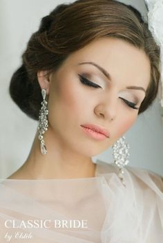 a woman in a wedding dress with her eyes closed and wearing earrings on her head