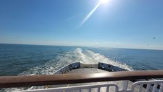 the back end of a boat traveling through the ocean on a sunny day with blue skies