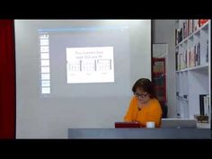 a woman sitting at a desk in front of a projector screen on the wall