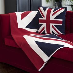 a red couch with two pillows on it and a blanket draped over the back of it