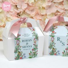 two small boxes with pink bows on them sitting next to each other in front of flowers