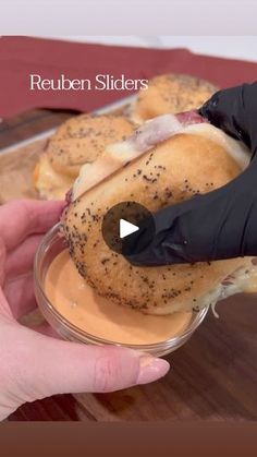 a person holding a sandwich in their hand with the words reuben sliders on it