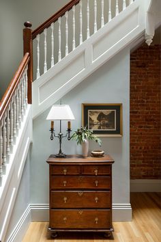 a wooden dresser sitting under a banister next to a stair case in a home