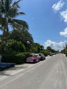 several cars parked on the side of a road with palm trees and blue skies in the background