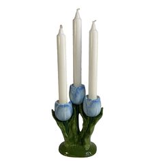 three white candles with blue flowers in a green vase