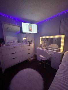 a bedroom with white furniture and purple lights on the ceiling, along with a flat screen tv