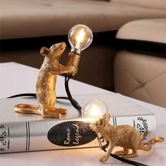 a lamp on top of a book with a mouse figurine next to it