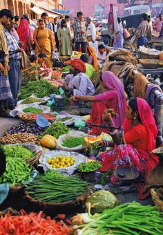 people are shopping at an outdoor market with fruits and vegetables on the ground in front of them